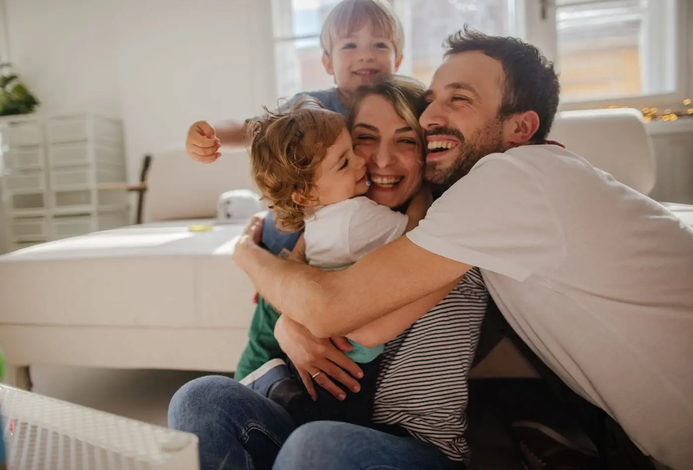 Familia feliz abrazándose y sonriendo en la sala de su hogar