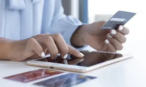 Mujer usando una tablet para pagos en línea con tarjeta de crédito.