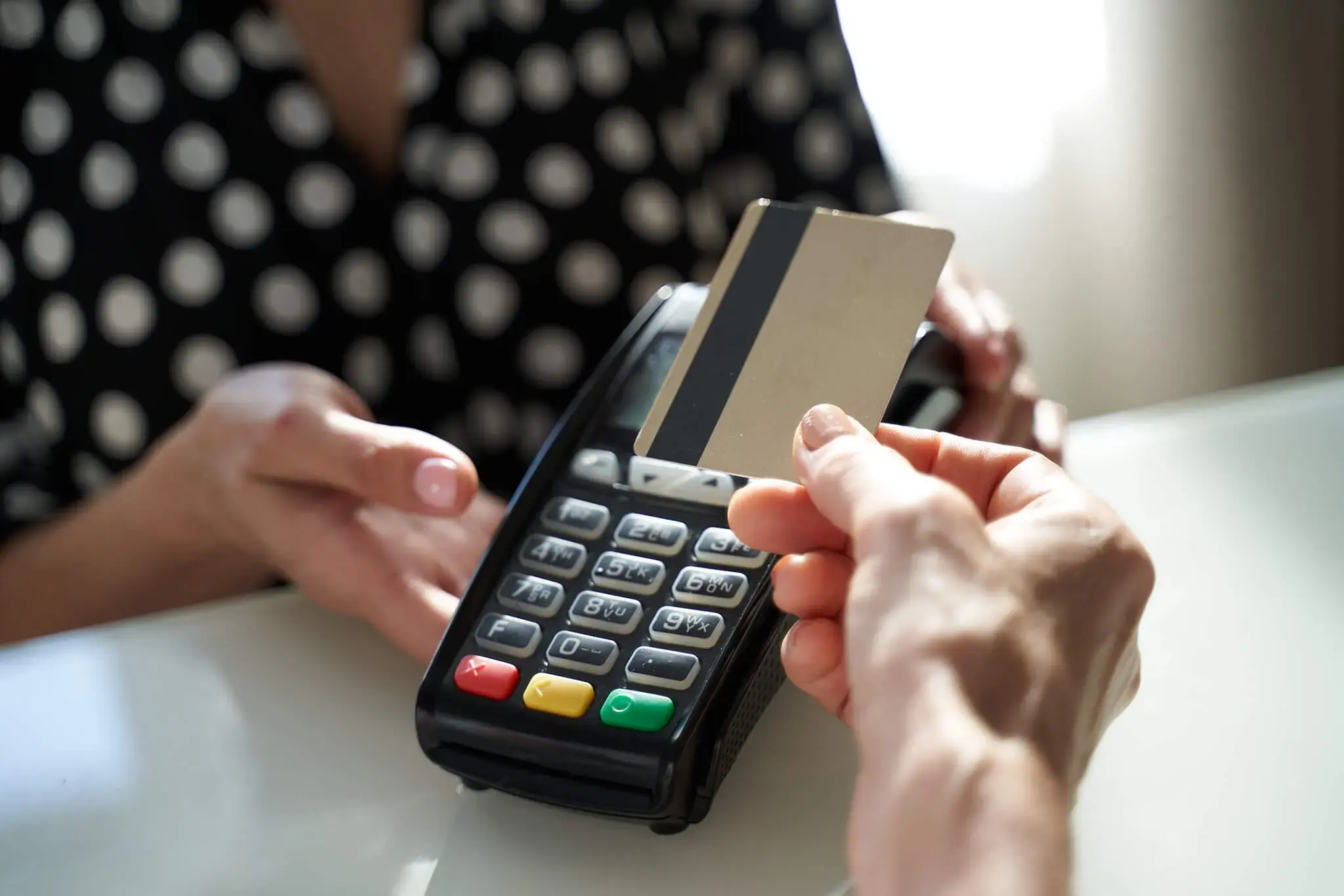 Persona realizando un pago con tarjeta de crédito o débito en un datáfono.