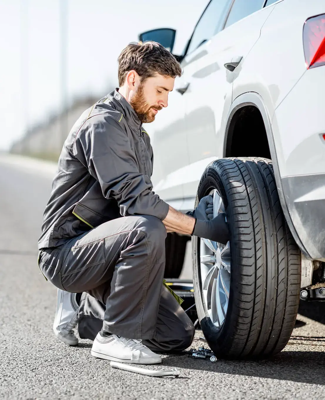 Hombre cambiando la llanta de un automóvil en la carretera.